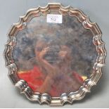 An antique Edwardian hallmarked sterling silver salver plate having pie crust edges and raised on