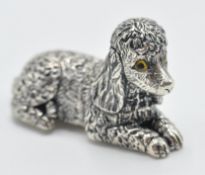 A sterling silver figurine of a poodle dog in a si