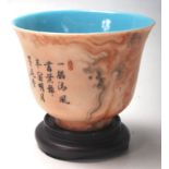 CHINESE TEA CUP RAISED ON A WOODEN BASE
