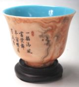 CHINESE TEA CUP RAISED ON A WOODEN BASE