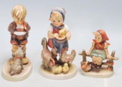 A group of German W. Goebel ceramic figurines to include a girl feeding the chickens, a boy and