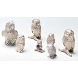 A group of seven vintage silver plated miniature owls sitting on a branch with heads twisted to
