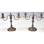 A pair of silver hallmarked candlesticks having twin branch candelabra with single sconces and wax