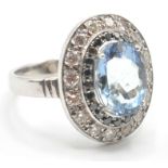 A 18CT WHITE GOLD RING SET WITH A CENTRAL AQUAMARINE AND BLACK AND WHITE DIAMONDS.