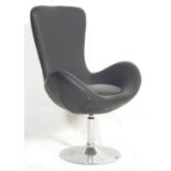 A late 20th century retro style Swan / swivel armchair with black faux leather upholstery raised