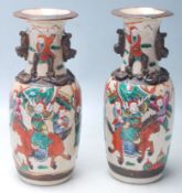 A pair of early 20th Century Chinese ceramic vases having a flared top with twin handles over hand