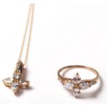 A 9ct gold ring set with pendant necklace. The gold ring having a flower shaped head with white