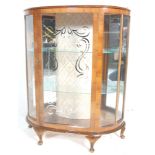 An early 20th century bow front walnut china display cabinet having twin sliding glass doors with