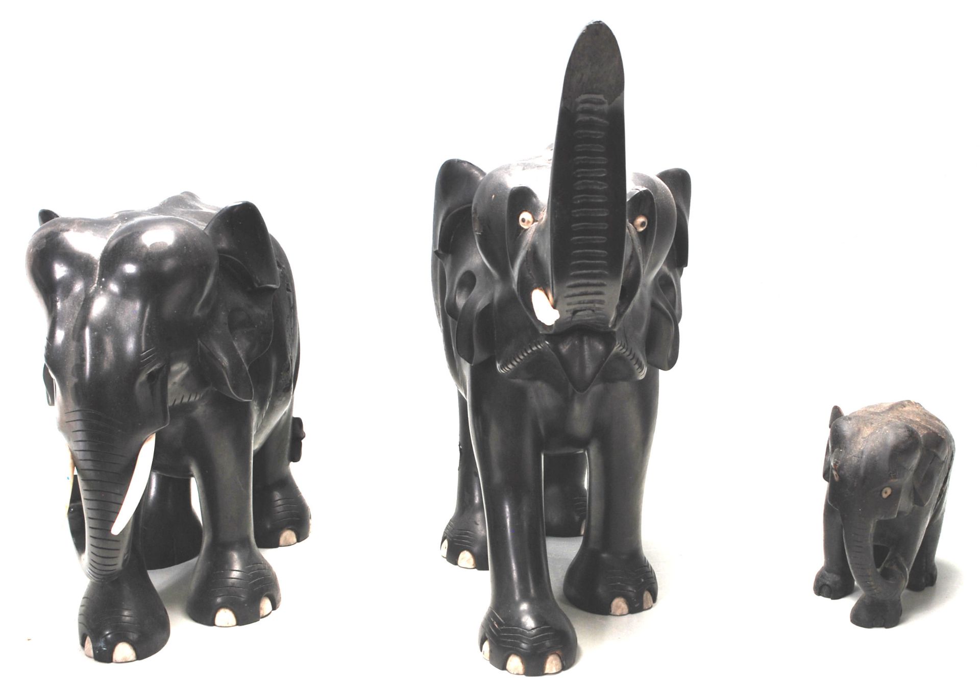 A collection of three antique 19th Century African ebony and ivory elephants of graduating height.