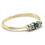 A hallmarked 18ct gold and platinum ring set with a green central stone flanked by 2 white stones.