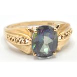 A hallmarked 9ct gold ring set with an oval cut mystic topaz style stone having tapering shoulders