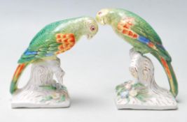 A PAIR OF EARLY 20TH CENTURY GERMAN CERAMIC PARROTS SET ATOP NATURALISTIC BASES.