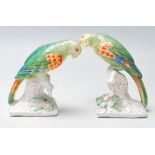 A PAIR OF EARLY 20TH CENTURY GERMAN CERAMIC PARROTS SET ATOP NATURALISTIC BASES.
