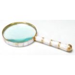 A BRASS AND FAUX MOTHER OF PEARL HAND HELD MAGNIFYING GLASS.