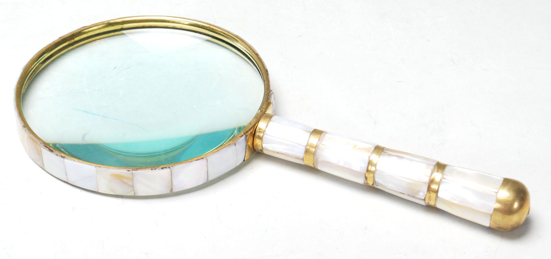 A BRASS AND FAUX MOTHER OF PEARL HAND HELD MAGNIFYING GLASS.