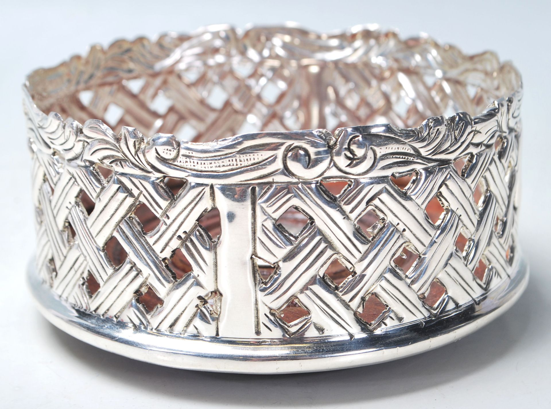 A SILVER PLATED WINE BOTTLE COAST HAVING PIERCED LATTICE DECORATION.