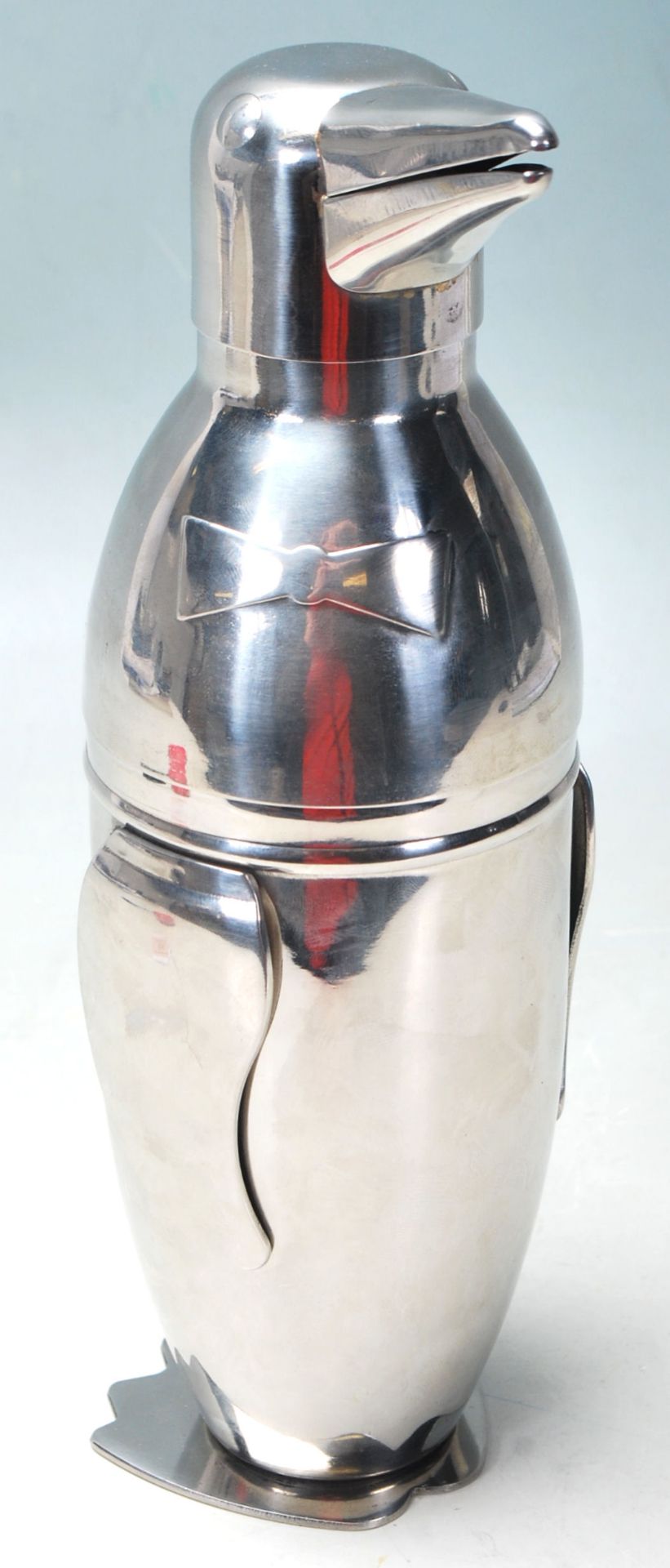 A STAINLESS STEEL COCKTAIL SHAKER IN THE FORM OF A PENGUIN WEARING A BOW TIE.