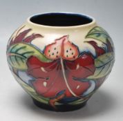 A VINTAGE MOORCROFT VASE OF BULBOUS FORM WITH FLORAL MOTIFS RAISED ON A CIRCULAR FOOT