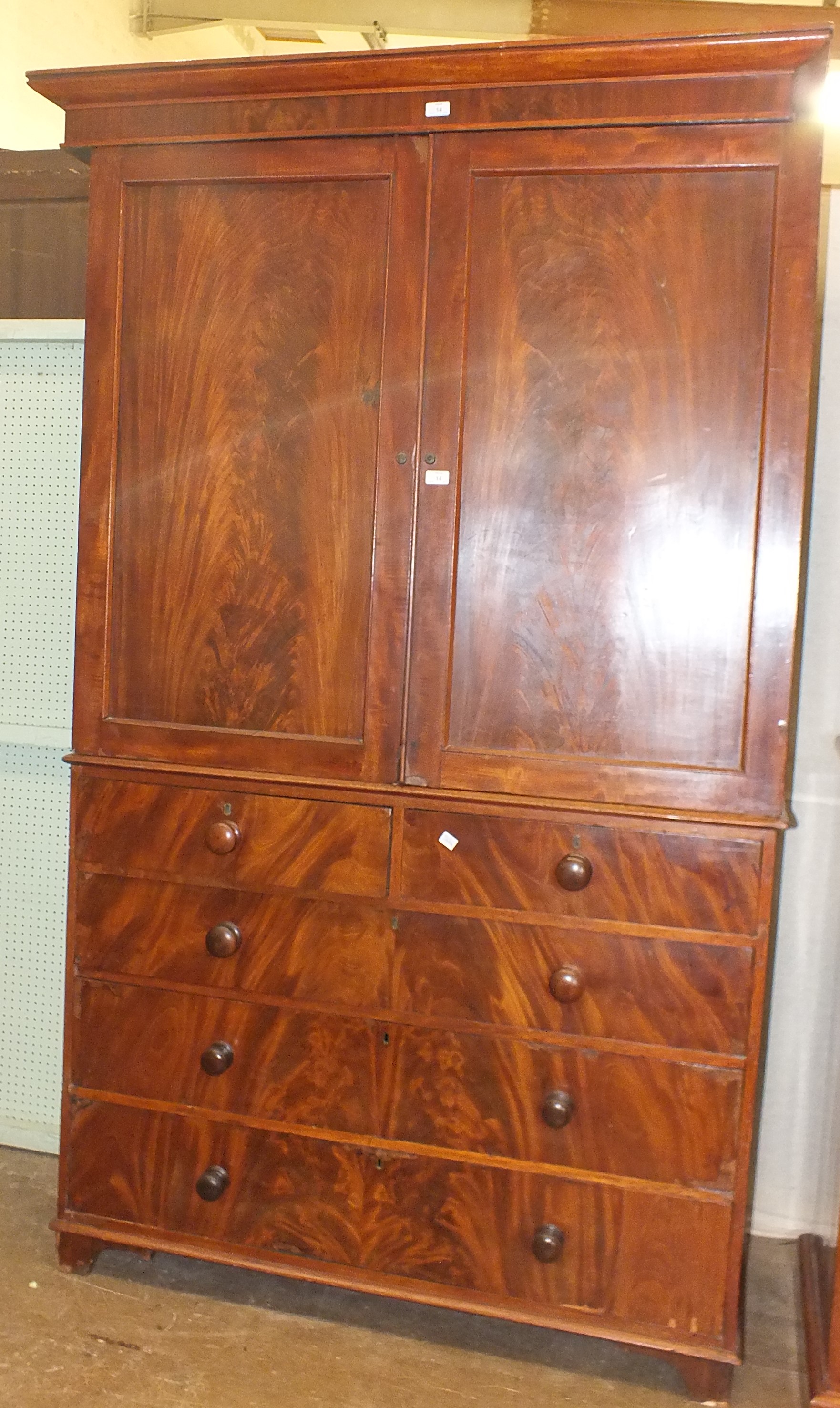 An early-19th century mahogany linen press, the pair of panelled doors enclosing three shelves,