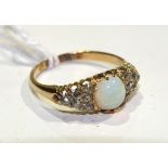 A Victorian opal and diamond ring set an oval opal between two triangular clusters.