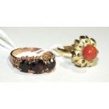 A modern Chinese 18ct gold ring set a coral bead, size L½, 2.9g and a 9ct gold ring set garnets.