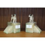 A pair of onyx book ends surmounted by painted spelter terriers, 12.5cm high.