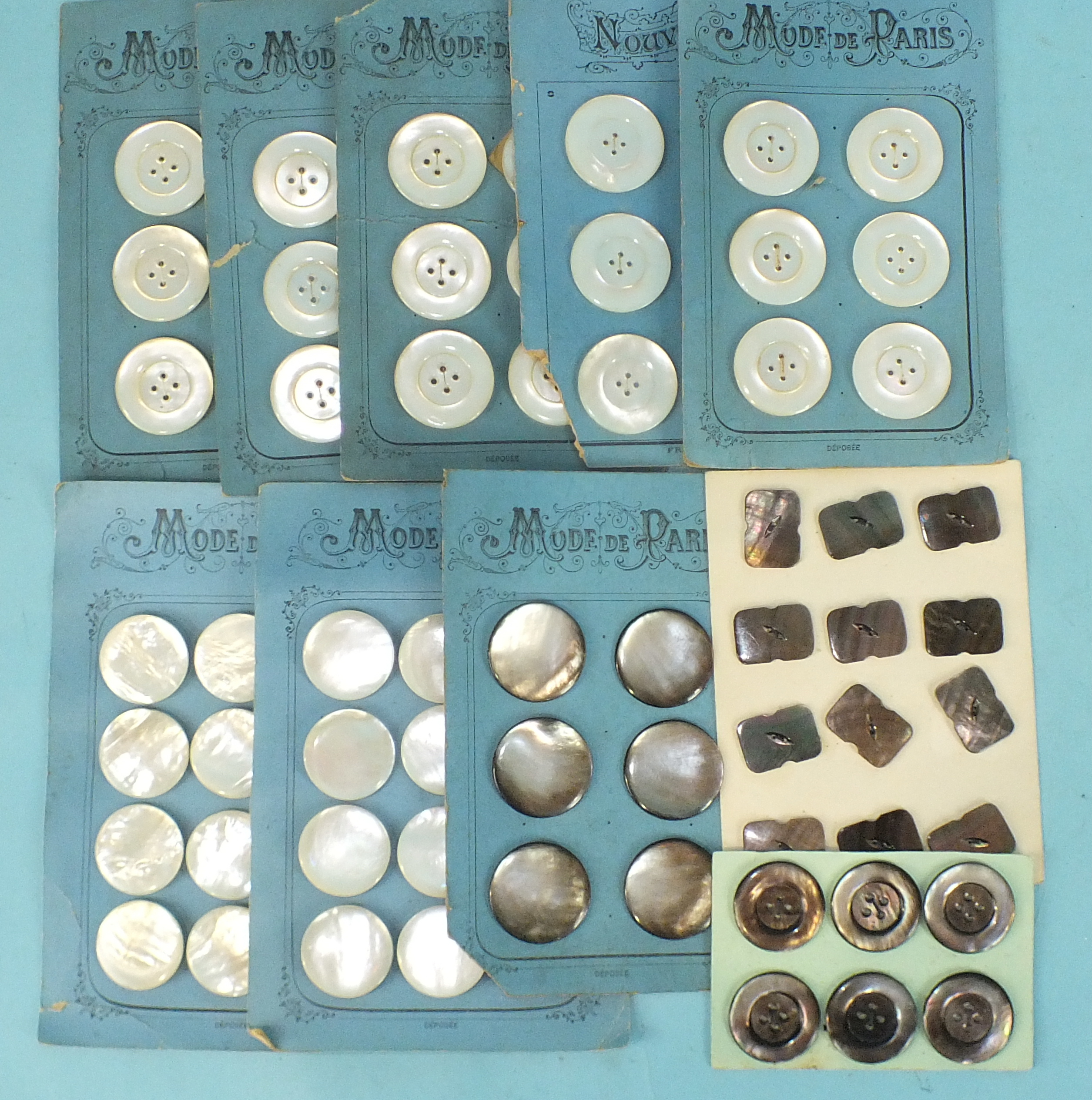 A collection of mother of pearl buttons on Mode de Paris haberdashery cards: 4cm diam (30), 3.5cm