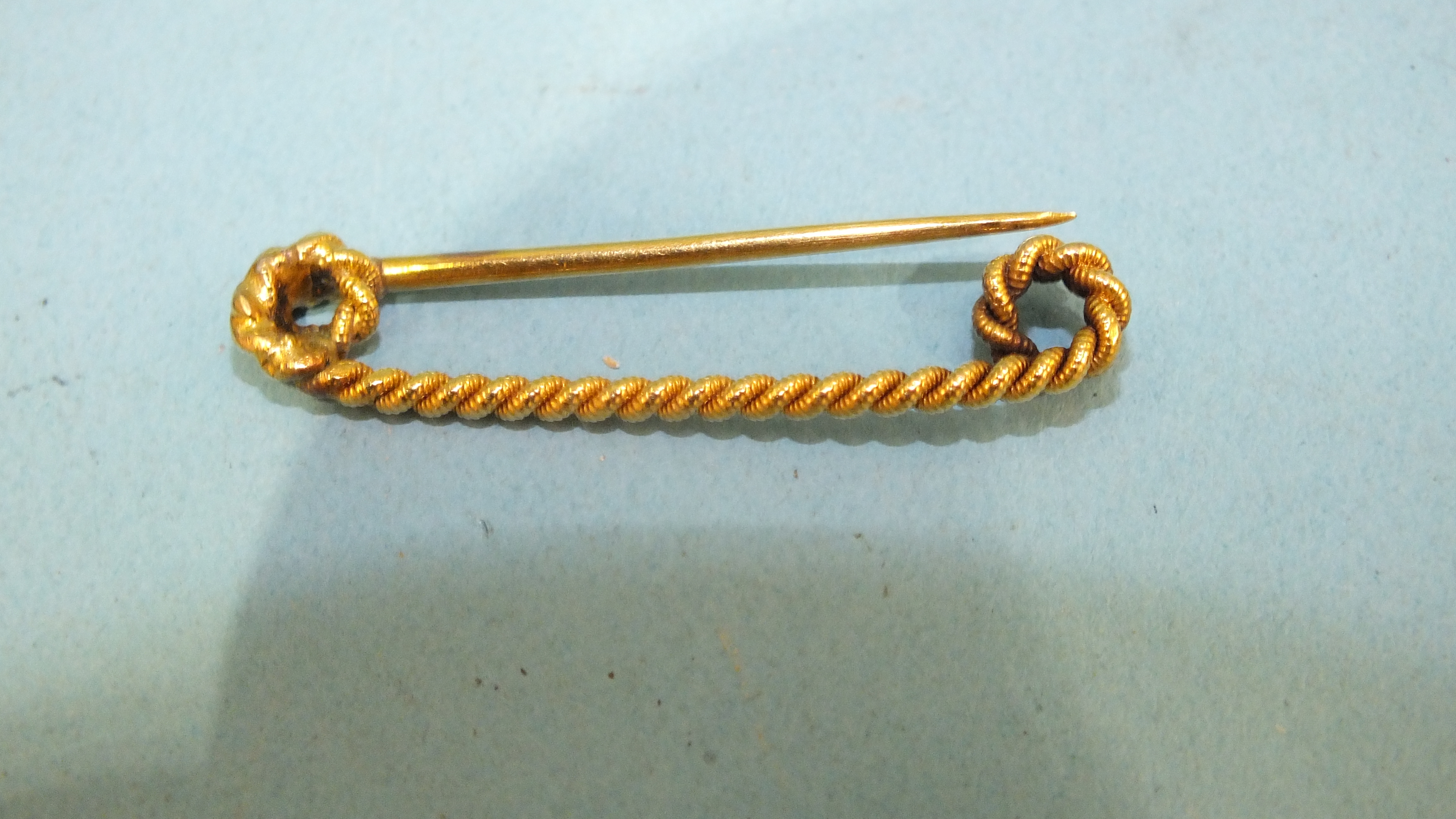 A yellow metal pin of twisted design, unmarked, 2.4g.