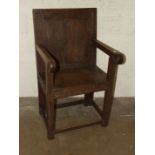 An antique oak hall chair, the carved panelled back and solid seat on square-form legs joined by