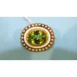 A late-Victorian oval brooch set peridot within concentric spotted white enamel and seed pearl