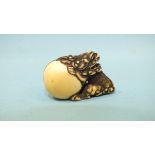 A fine late-18th/early-19th century ivory netsuke of a seated shishi pushing a large ball, its