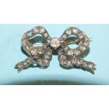 A late-Victorian bow brooch, the knot set an old brilliant-cut diamond between graduated rose-cut