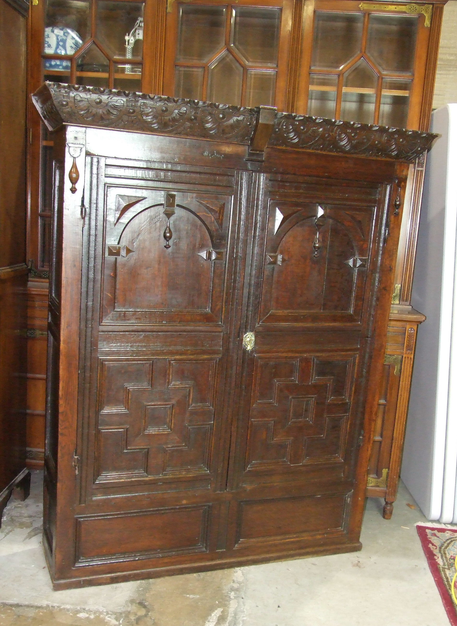 An antique oak cupboard, the carved cornice above a pair of panelled doors, 136cm wide, 165cm high.