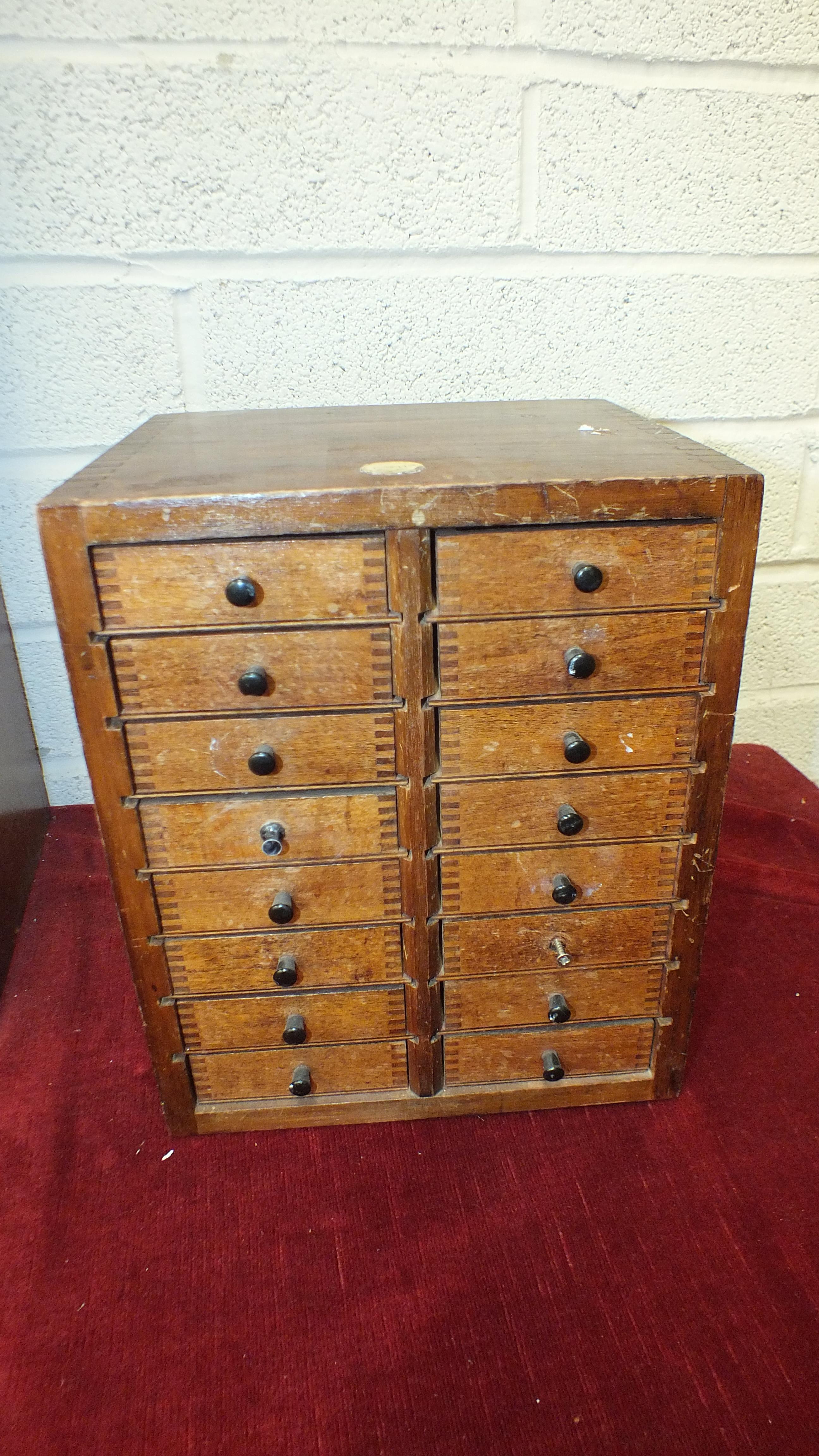 A stained wood nest of sixteen small drawers, labelled Ashford, England, 24cm wide, 31cm high.