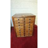 A stained wood nest of sixteen small drawers, labelled Ashford, England, 24cm wide, 31cm high.