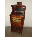 A Victorian walnut music cabinet, the mirrored top above a glazed door and pull-down music drawer,