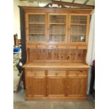 A modern pine kitchen dresser having three glazed doors and three small drawers above three