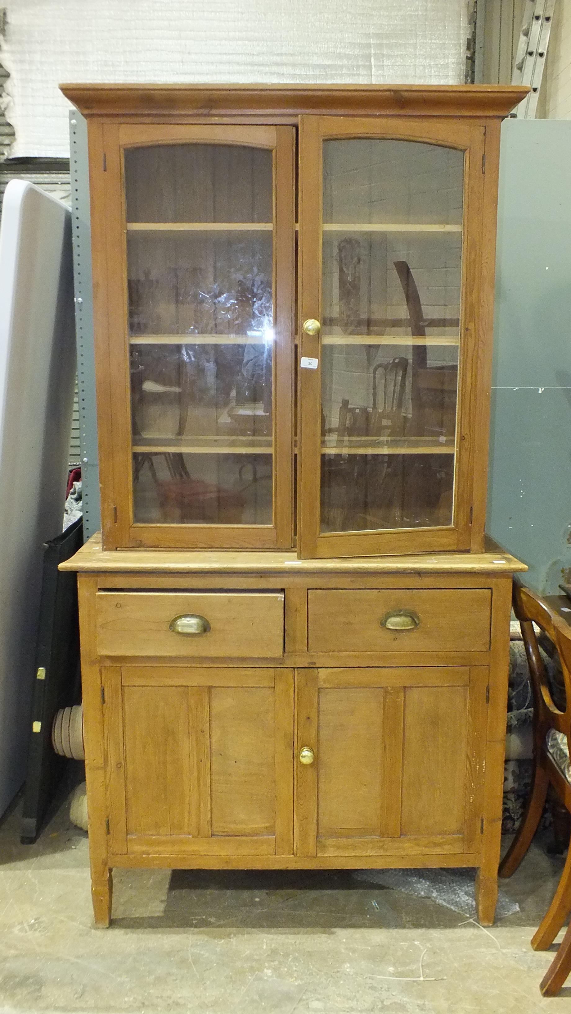 A pine and ply kitchen dresser fitted with two glazed doors, above two drawers and two panelled