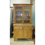 A pine and ply kitchen dresser fitted with two glazed doors, above two drawers and two panelled