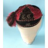 An early 20th century maroon and black velvet sporting cap with gold braid initials C C and dated