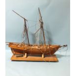 A wooden model of a two-masted sailing ship, deck detail includes eight cannon, barrels, capstan,