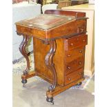 A late-Victorian walnut Davenport, the lift top on carved scroll supports, with four side drawers