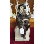 An Art-Deco-style bronzed metal and faux ivory figure of a clown seated on a pedestal and playing