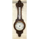 An aneroid barometer/thermometer with carved oak case, 87cm high.