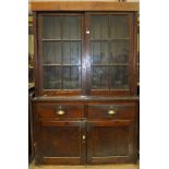 A stained pine kitchen dresser, the top with sliding glass doors, above two drawers and two cupboard