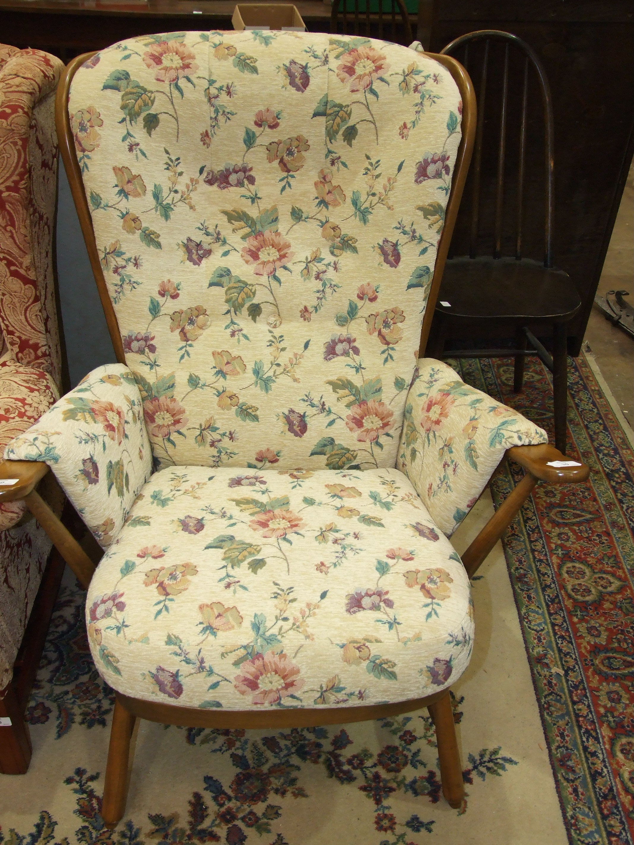 An Ercol stained wood stick-back armchair, with button upholstery.