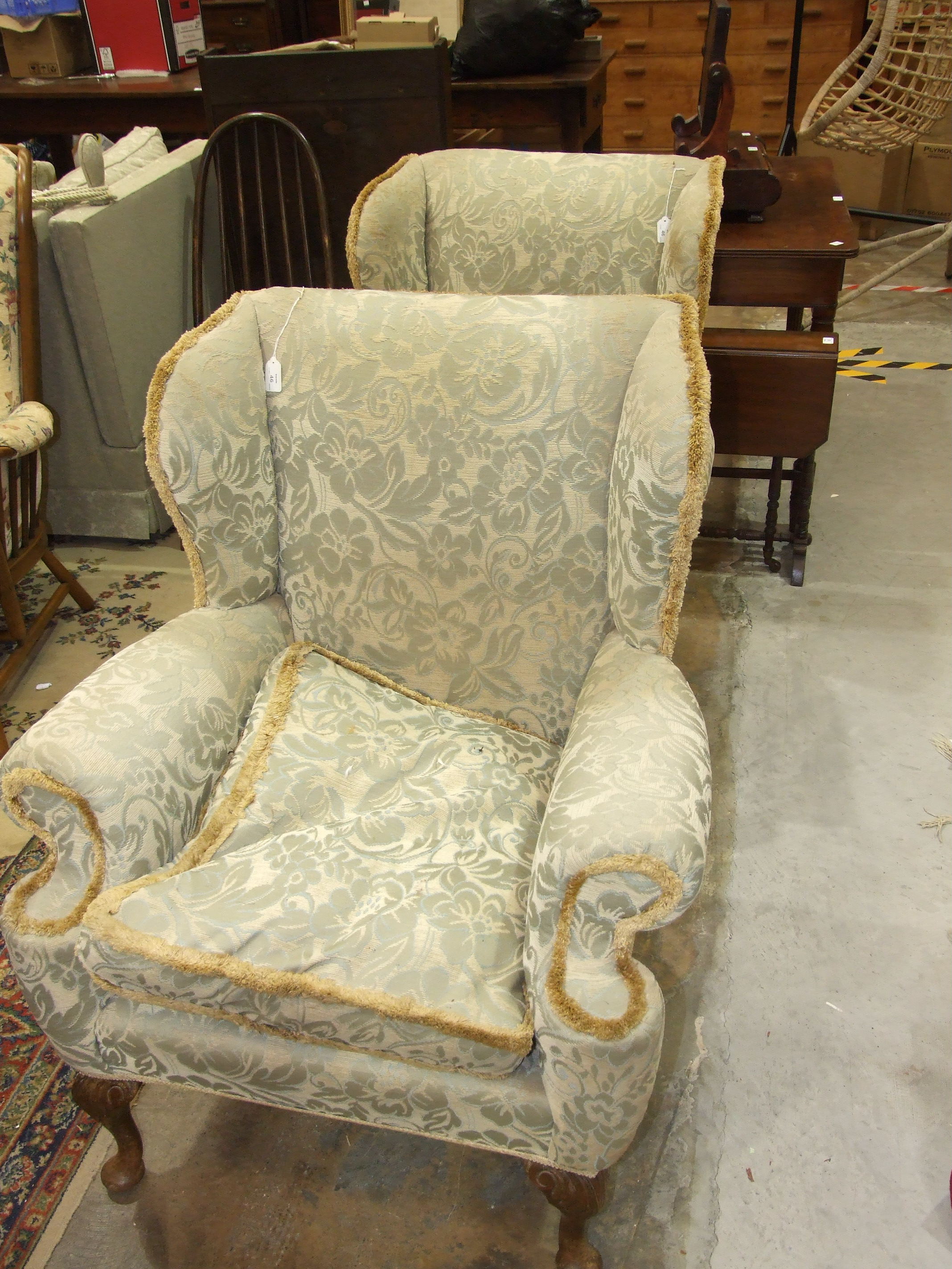A pair of Georgian-style wing armchairs on cabriole front legs.