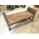 A 20th century stained hardwood long foot stool, with woven leather seat and low arms, on turned