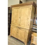 An antique pine housekeeper's cupboard, the cornice above four panelled doors enclosing shelves,