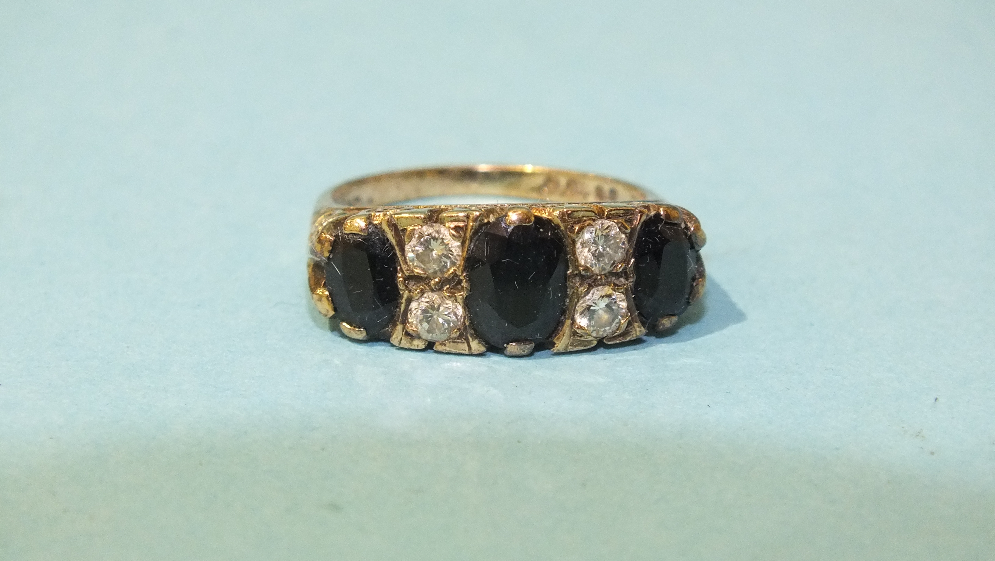 A 9ct gold ring set three oval sapphires and two pairs of brilliant-cut diamonds, size M, 4g.